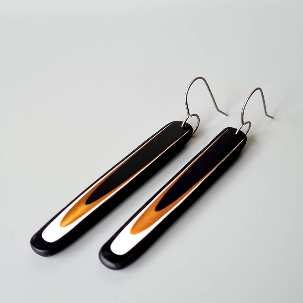 Handmade long dangle earrings with a clean, modern pattern in black, gold and white. Hand crafted titanium earwires.